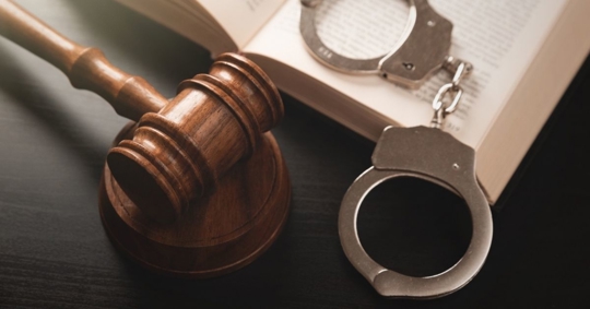 gavel, book, and handcuff on a table