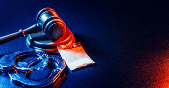 drugs next to gavel and handcuffs